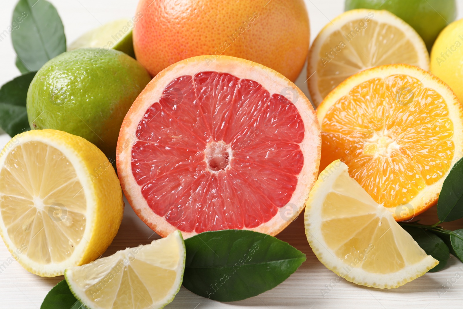 Photo of Different cut and whole citrus fruits on white table, closeup