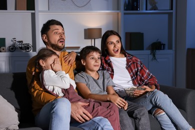 Photo of Emotional family watching TV at home in evening