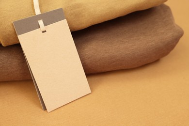 Photo of Garment with cardboard tag on kraft paper sheet, closeup. Space for text