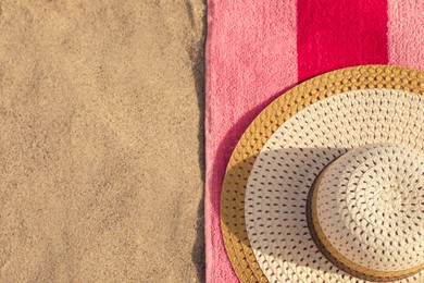 Beach towel and straw hat on sand, flat lay. Space for text