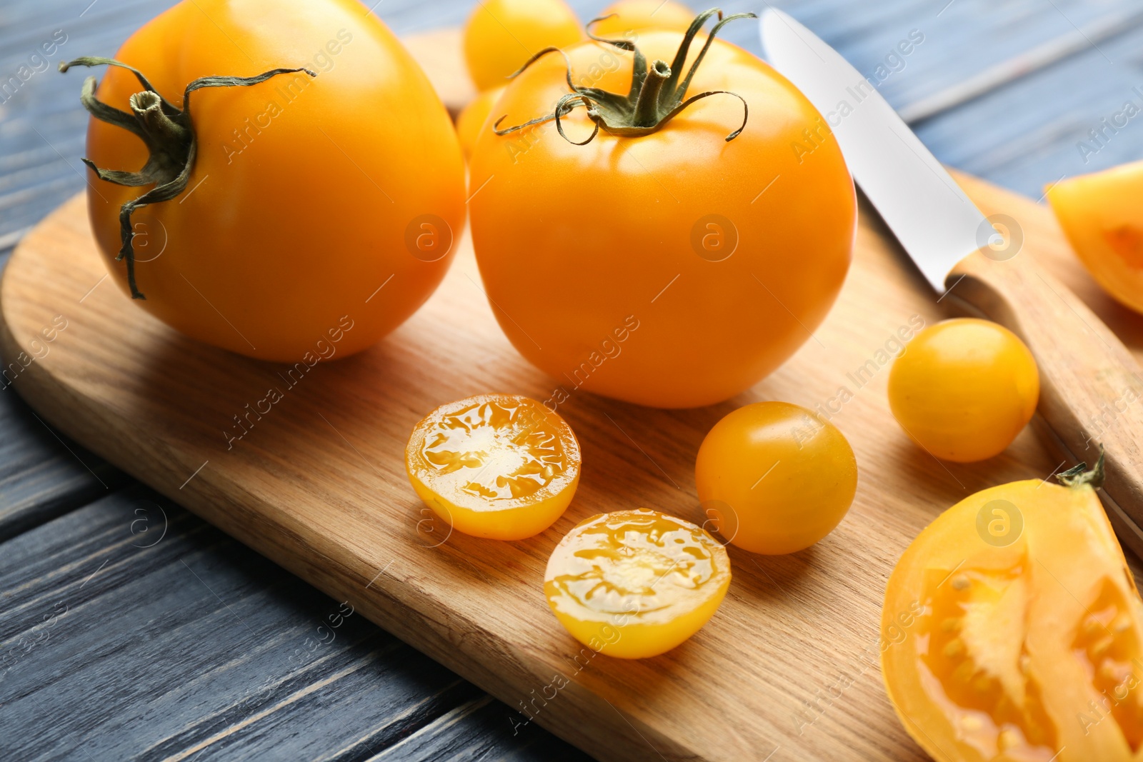 Photo of Ripe yellow tomatoes on wooden board, closeup