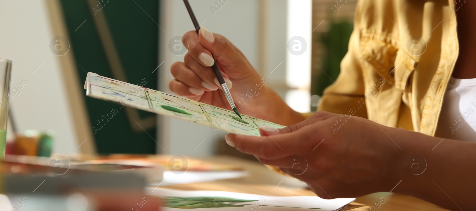 Image of Young woman drawing leaf at table indoors, closeup. Banner design