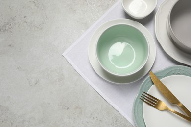 Photo of Beautiful ceramic dishware and cutlery on light grey table, top view. Space for text