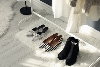 Photo of Faux fur rug with stylish women's shoes indoors. Interior design