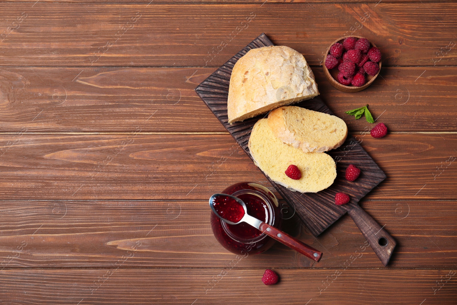 Photo of Beautiful composition with delicious raspberry jam on wooden table, top view