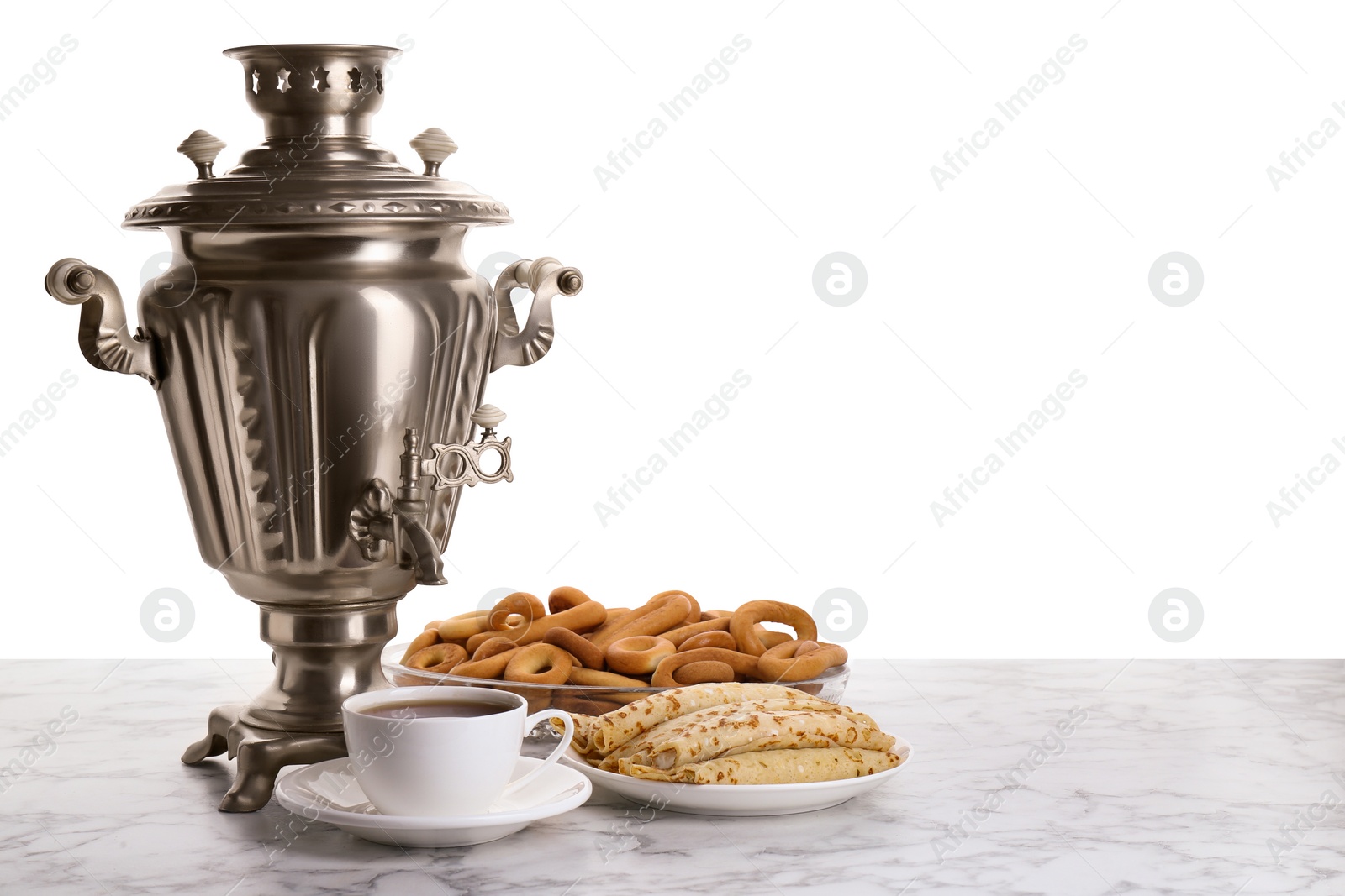 Photo of Vintage samovar, cup of hot drink and snacks on marble table against white background, space for text. Traditional Russian tea ceremony