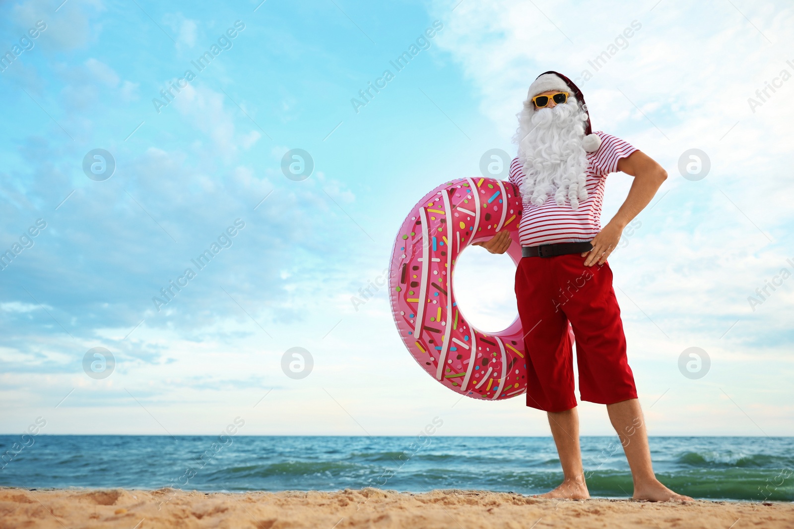 Photo of Santa Claus with inflatable ring on beach, space for text. Christmas vacation