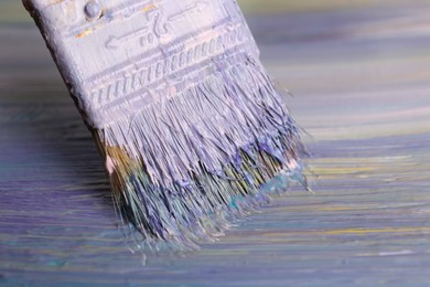 Photo of Strokes of colorful paints and brush on canvas, closeup