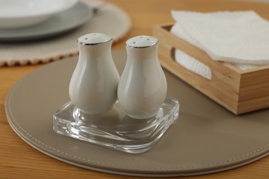 Photo of White ceramic salt and pepper shakers on wooden table