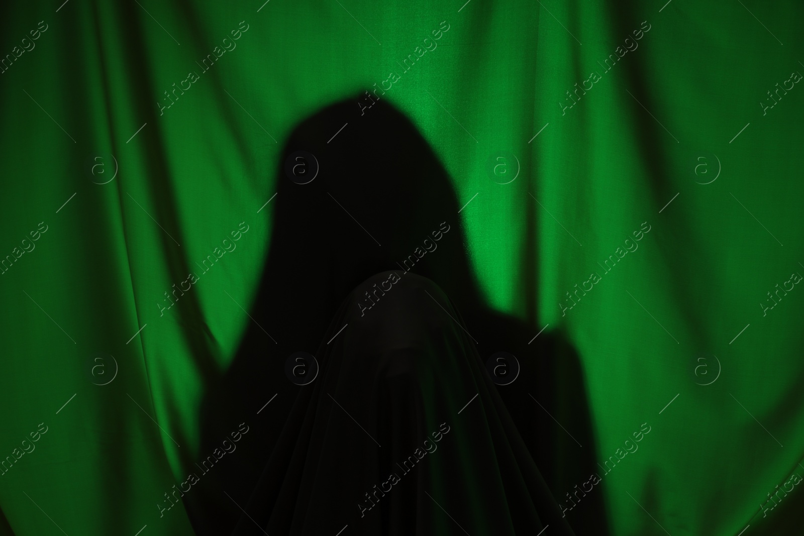 Photo of Silhouette of creepy ghost behind dark green cloth