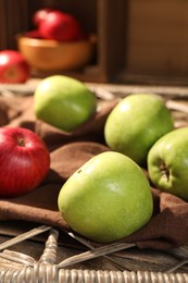 Photo of Fresh colorful apples on rattan grid, closeup
