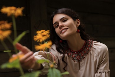 Photo of Beautiful woman wearing ornate beaded necklace in blooming garden. Ukrainian national jewelry