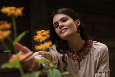 Beautiful woman wearing ornate beaded necklace in blooming garden. Ukrainian national jewelry