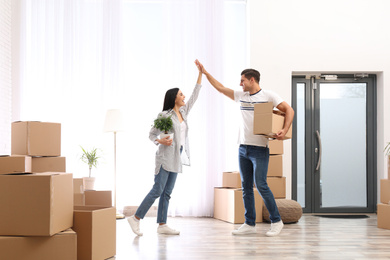 Happy couple in room with cardboard boxes on moving day