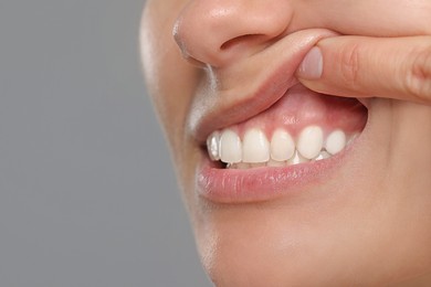 Photo of Woman showing healthy gums on gray background, closeup. Space for text