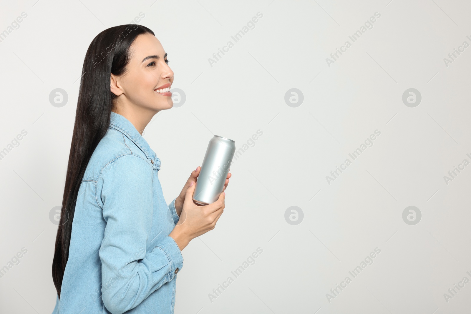 Photo of Beautiful happy woman holding beverage can on light grey background. Space for text