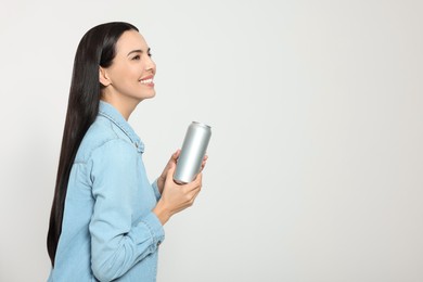 Photo of Beautiful happy woman holding beverage can on light grey background. Space for text