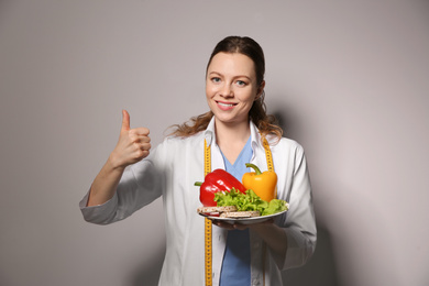 Nutritionist with healthy products on light grey background