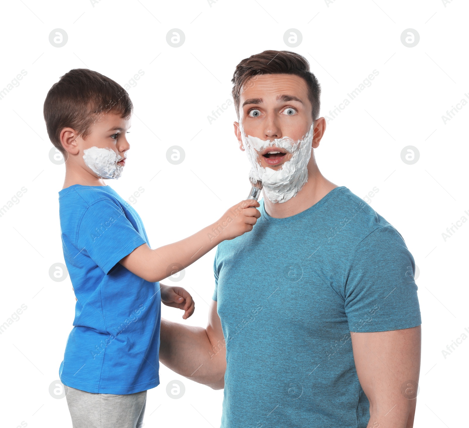 Photo of Little son applying shaving foam onto dad's face against white background