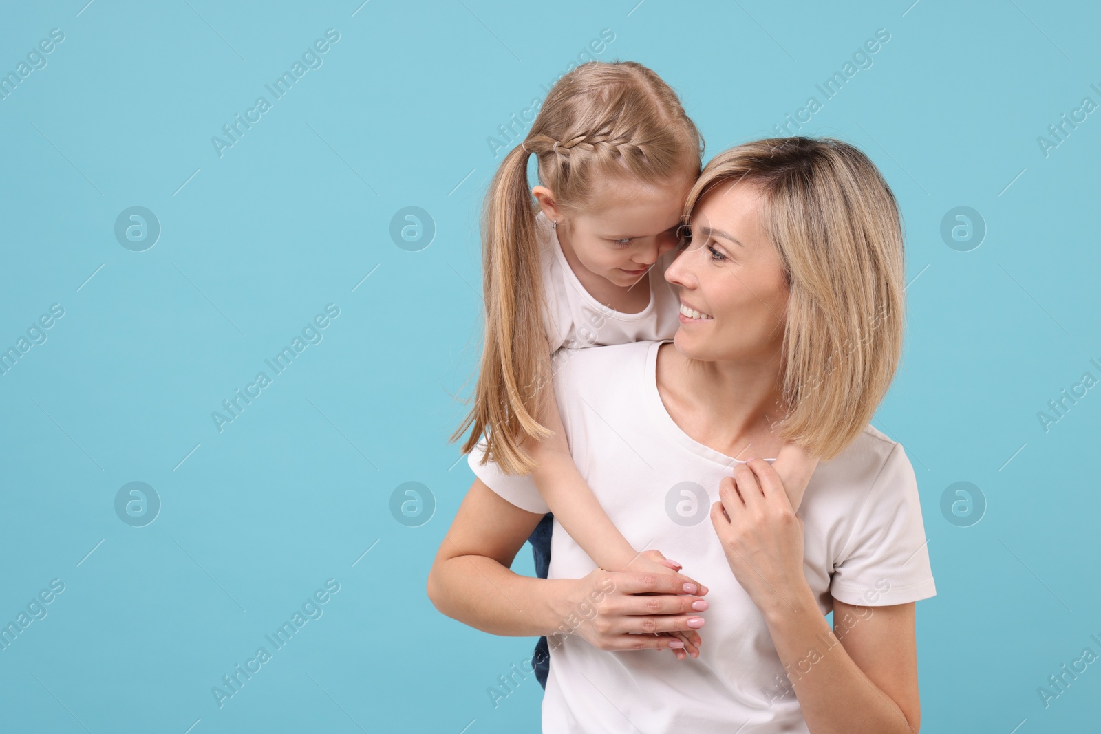 Photo of Family portrait of happy mother and daughter on light blue background. Space for text