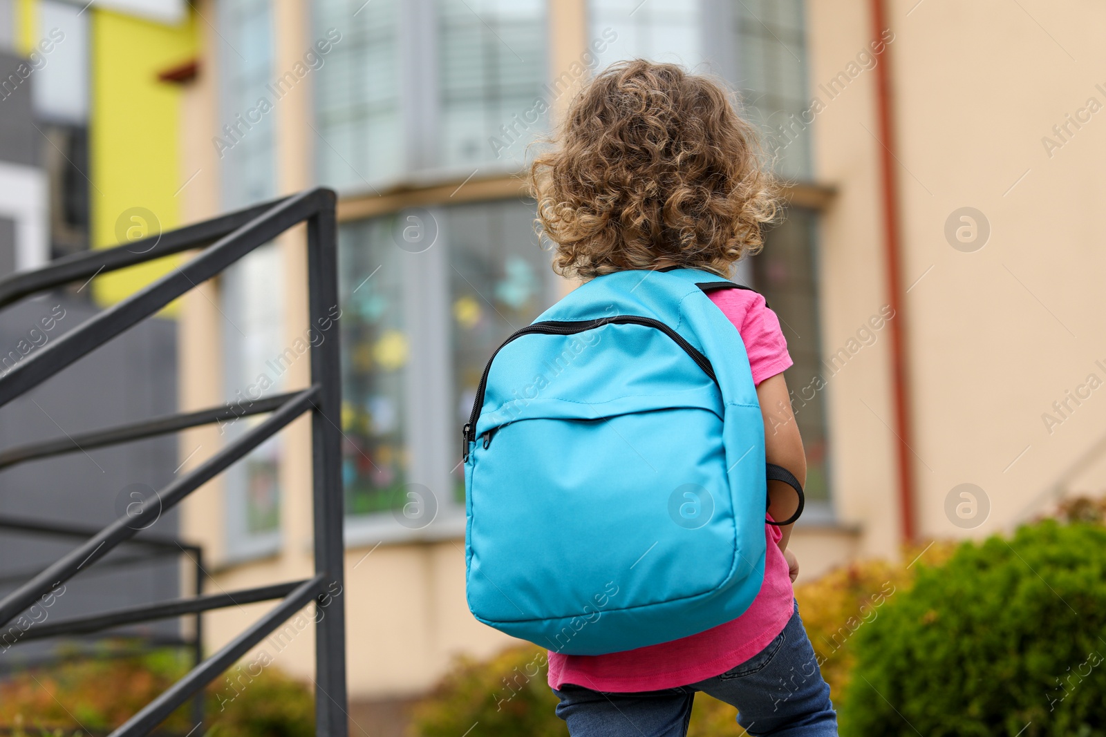 Photo of Little girl walking to kindergarten outdoors, back view. Space for text