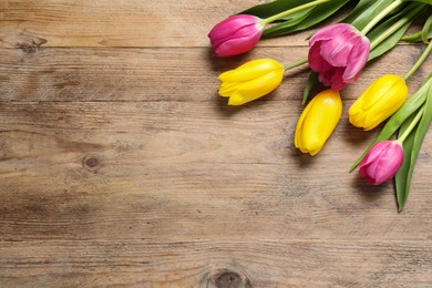 Photo of Beautiful colorful tulip flowers on wooden table, flat lay. Space for text