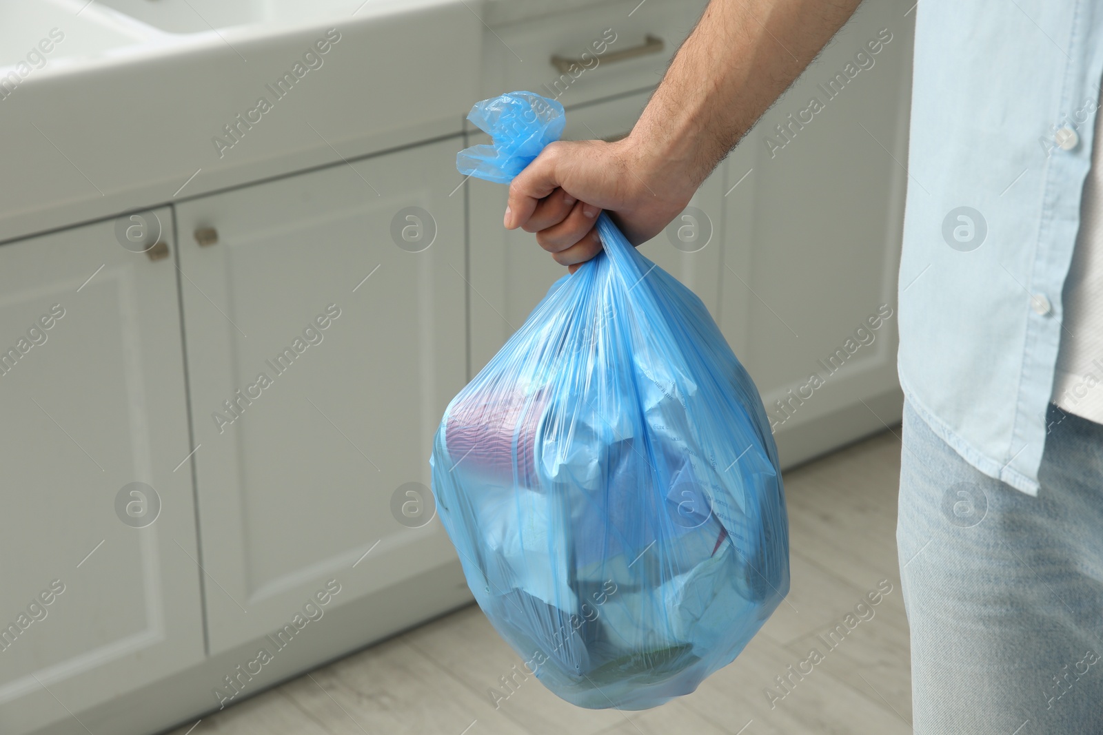 Photo of Man holding full garbage bag at home, closeup