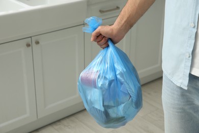Photo of Man holding full garbage bag at home, closeup