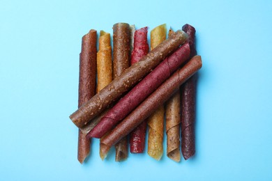 Delicious fruit leather rolls on light blue background, flat lay