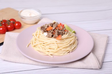 Photo of Tasty minced meat with spaghetti and vegetables on white wooden table