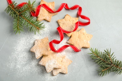Photo of Tasty homemade Christmas cookies with ribbon and fir tree twigs on table, top view