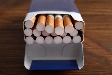 Photo of Pack of cigarettes on wooden table, closeup