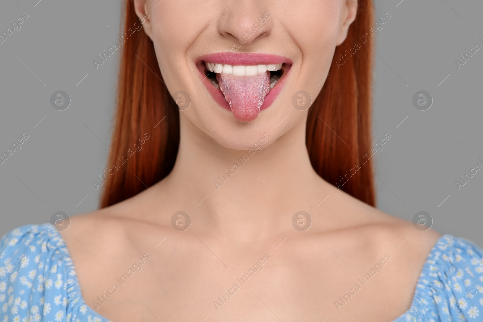 Photo of Happy woman showing her tongue on gray background, closeup