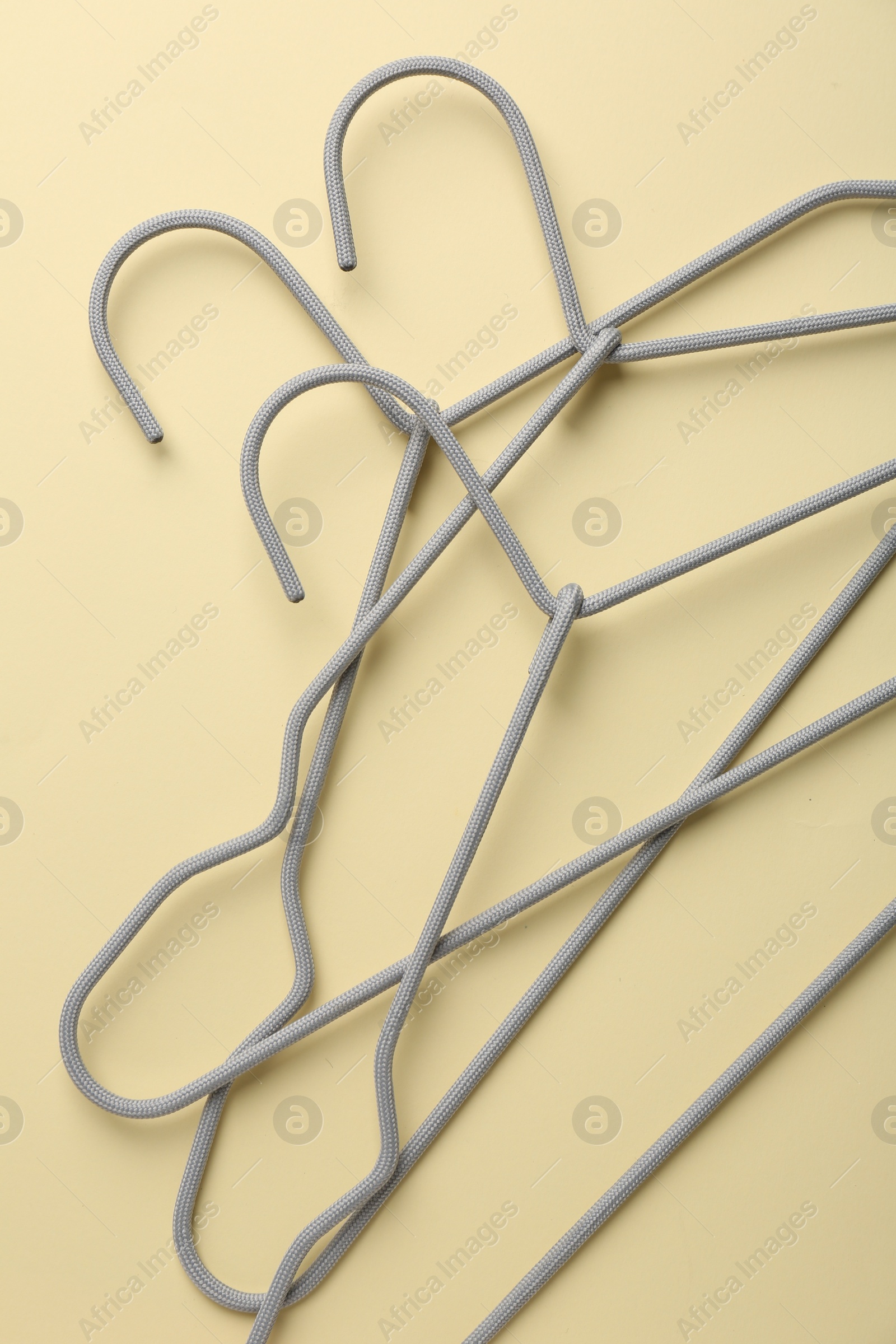 Photo of Hangers on pale yellow background, flat lay