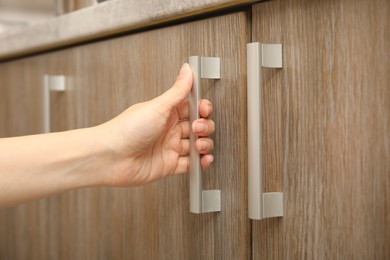 Photo of Woman opening cabinet door at home, closeup