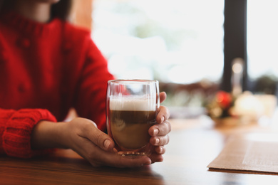 Woman with fresh morning coffee at table in cafe, closeup