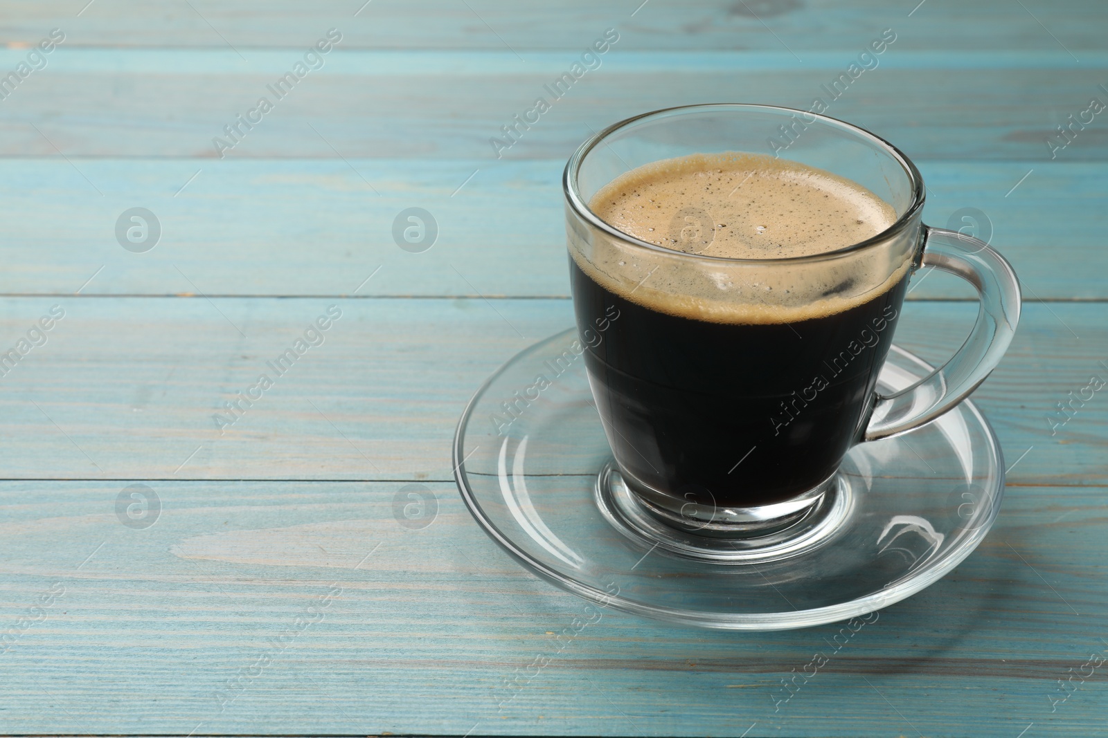 Photo of Cup of aromatic coffee on light blue wooden table, closeup. Space for text