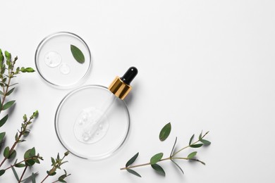Petri dishes with samples of cosmetic oil, pipette and green leaves on white background, flat lay. Space for text