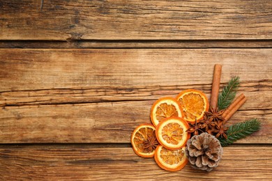 Photo of Dry orange slices, cinnamon sticks, fir branches and anise stars on wooden table, flat lay with space for text