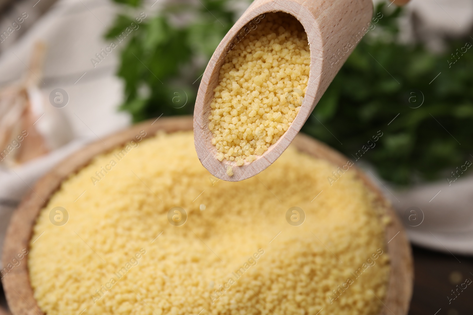 Photo of Taking raw couscous with scoop from bowl, closeup