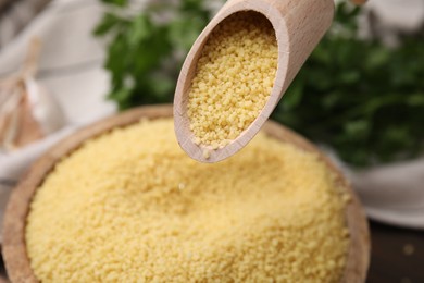 Photo of Taking raw couscous with scoop from bowl, closeup