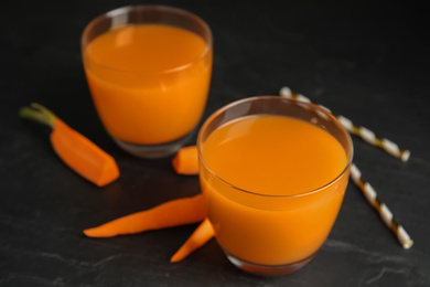 Photo of Glasses of freshly made carrot juice on black table