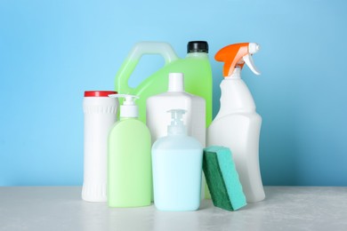 Photo of Different cleaning supplies and tools on table against light blue background