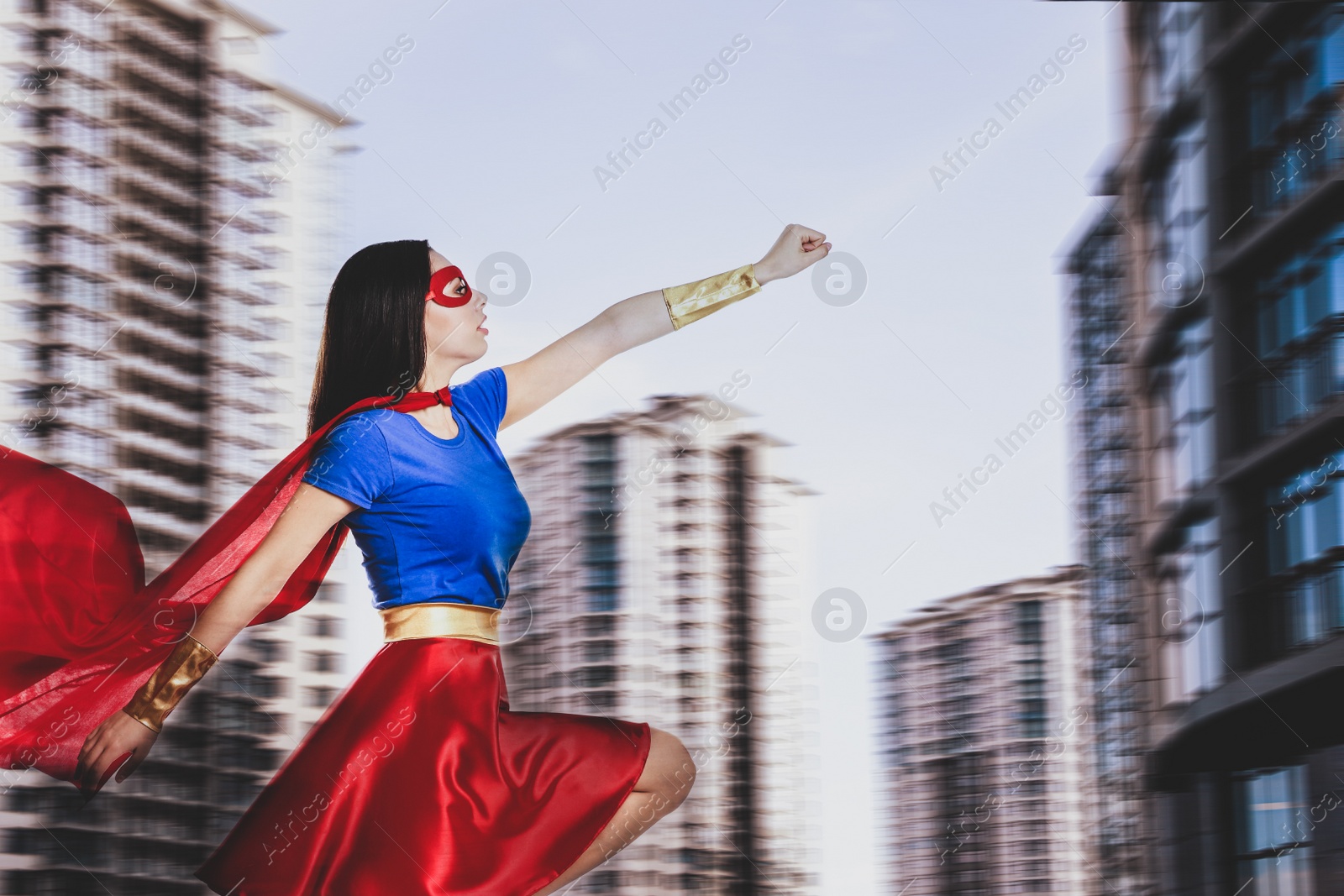 Image of Confident young woman wearing superhero costume and beautiful cityscape on background