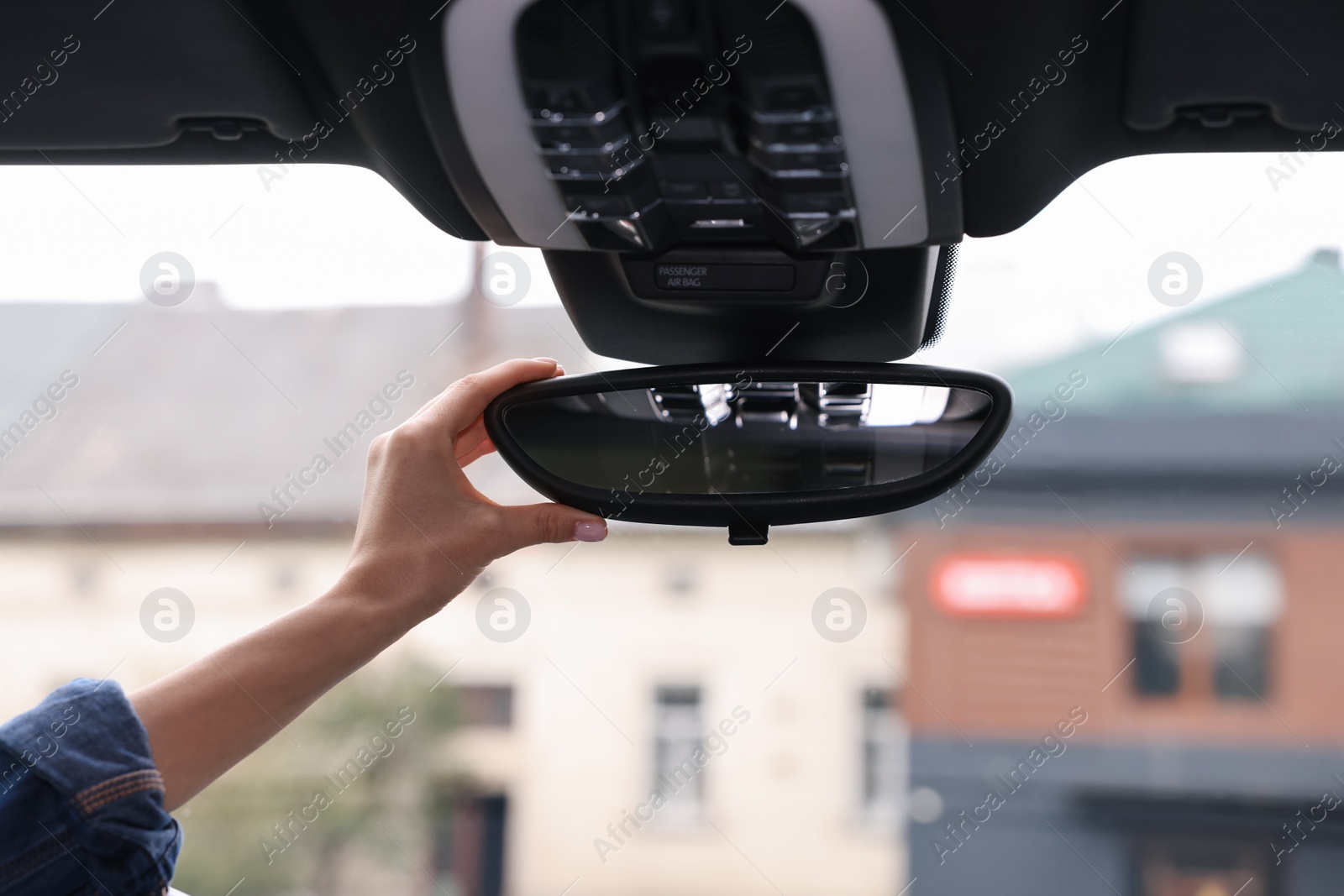 Photo of Woman adjusting rear view mirror inside her car, closeup