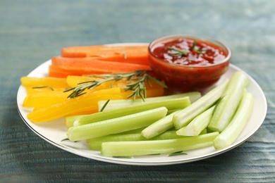 Celery and other vegetable sticks with dip sauce on light blue wooden table, closeup