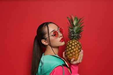 Photo of Young woman with fresh pineapple on red background. Exotic fruit