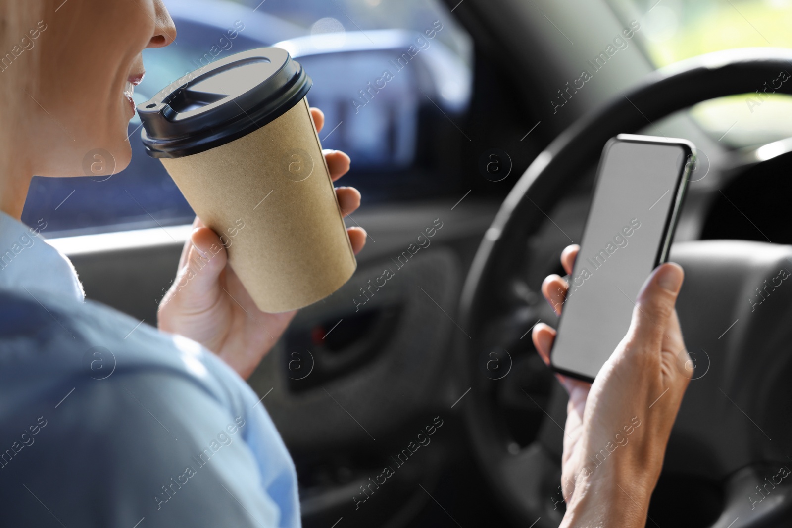 Photo of To-go drink. Woman with smartphone drinking coffee in car, closeup