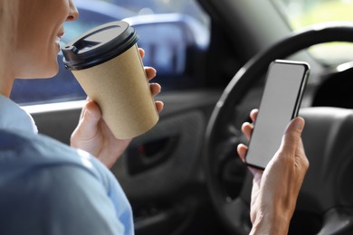 Photo of To-go drink. Woman with smartphone drinking coffee in car, closeup