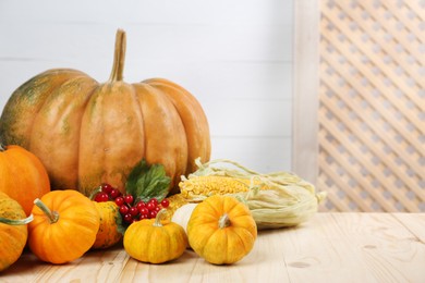 Photo of Happy Thanksgiving day. Composition with pumpkins, corn cobs and berries on wooden table. Space for text